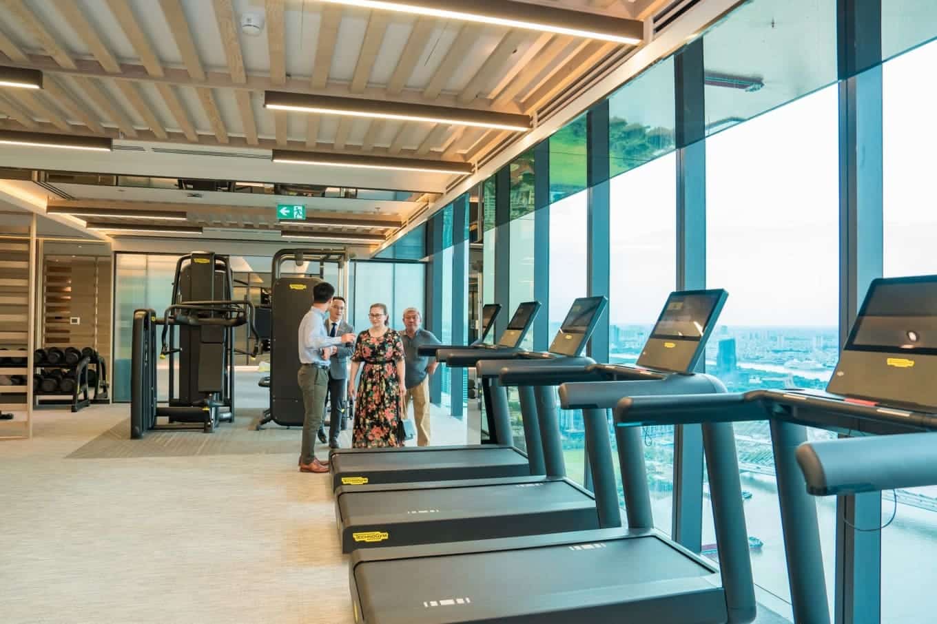Quản gia Marriott hướng dẫn cư dân sử dụng các tiện ích tại phòng gym với thiết bị hiện đại cùng tầm nhìn toàn cảnh TP HCM.